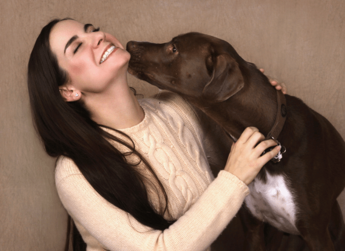 A woman getting kissed by her dog