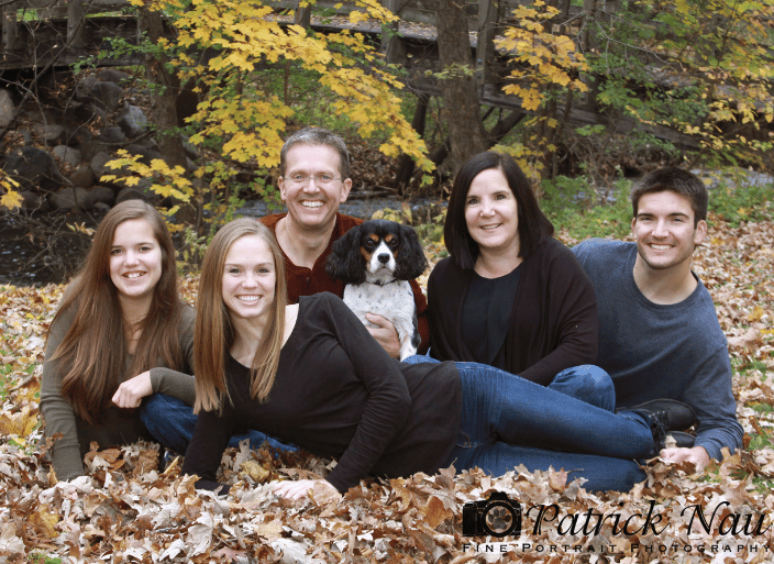 A portrait of a family in the park with their dog