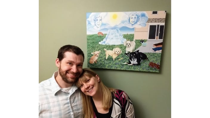 Happy couple with their 18x24" memorial painting of 4 dogs they dearly loved.