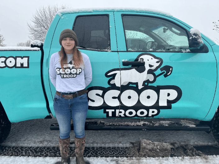 Scoop Troop Employee standing in front of a Scoop Troop branded truck. 