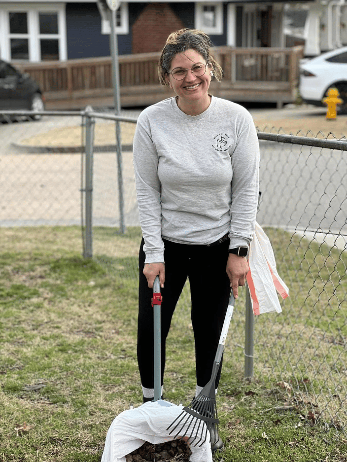 Employee with branded shirt and actively scooping a clients yard