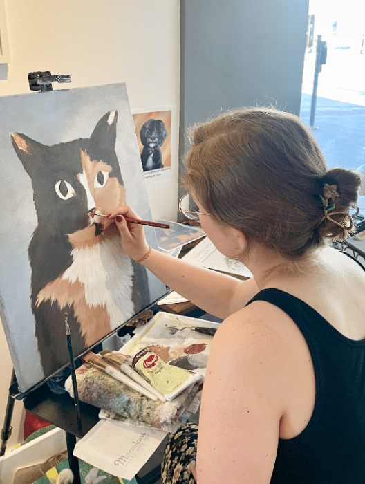Me working on a pet portrait painting commission of a calico cat.