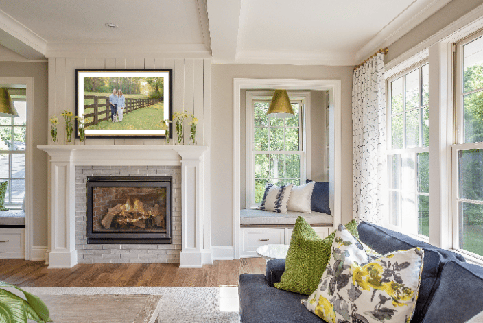 A man & woman stand along a wooden fence with a yellow labrador puppy at their feet in a framed photo above the fireplace in a homey Atlanta living room.