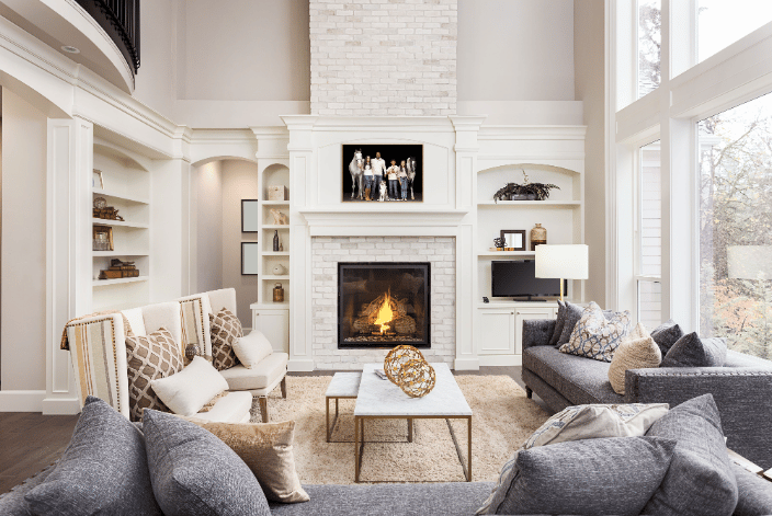 A family poses with their 2 horses & 2 dogs against a black background in a framed photo above a white fireplace in an upscale Atlanta suburban home.
